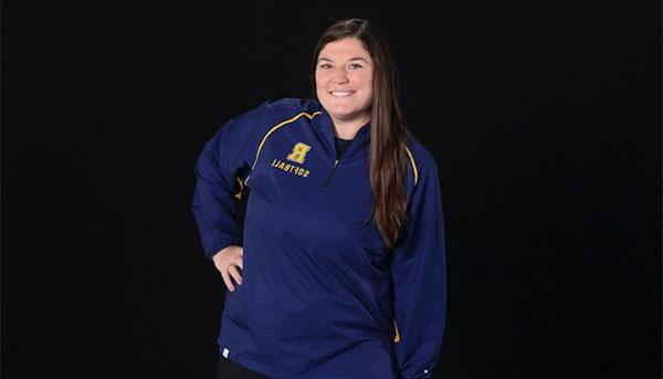 Abby Hurley-Martin posing in front of black background wearing blue Rochester R shirt