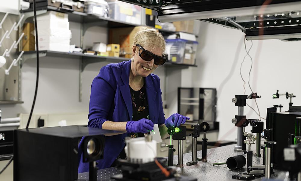 woman scientist waring safety glasses and gloves in a lab