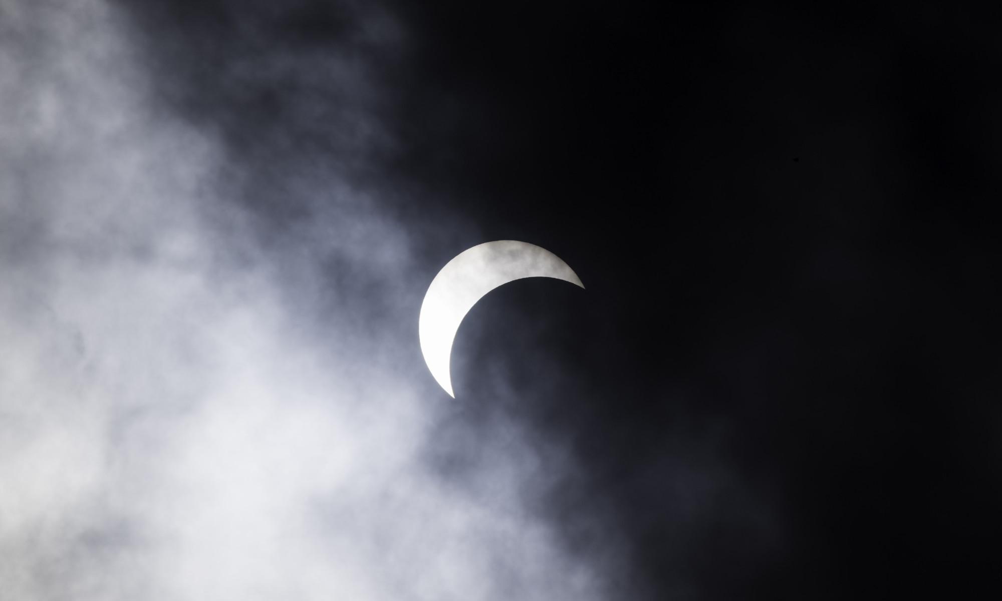 Partial solar eclipse seen through clouds.